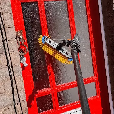 Professional window cleaner washing a red door in Luton